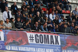 A large group of Max Verstappen, Red Bull Racing, supporters sit above a banner in the grandstand