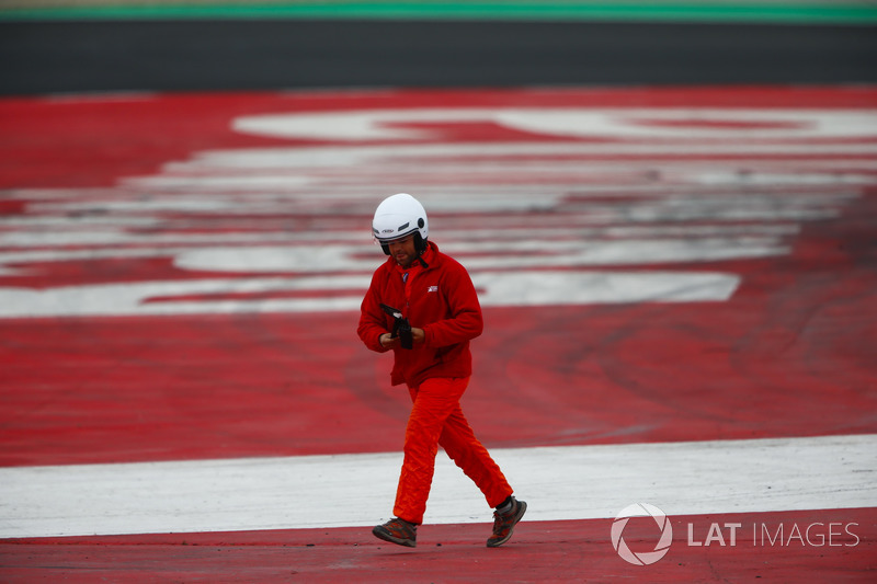 A marshal picks up a piece of debris from the track