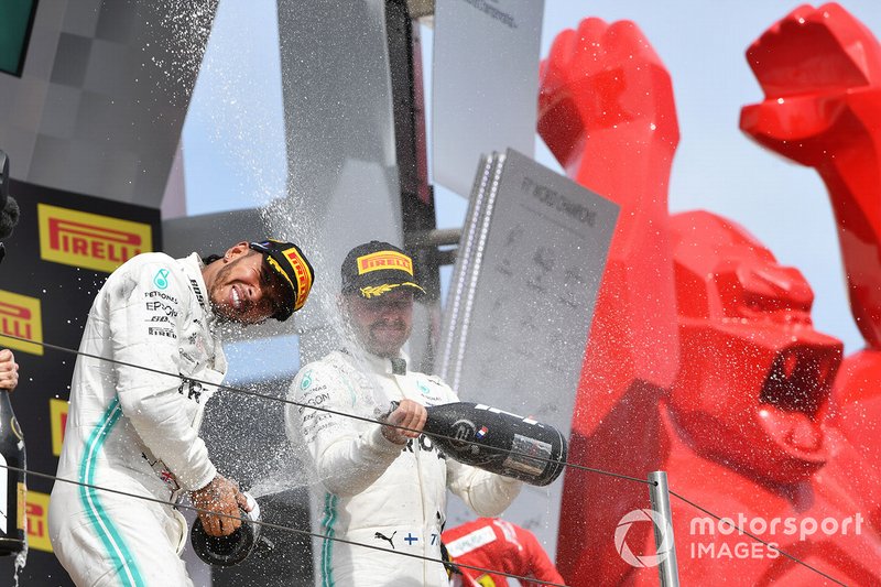 Lewis Hamilton, Mercedes AMG F1, pemenang balapan, and Valtteri Bottas, Mercedes AMG F1, runner up, menyemprot sampanye di atas podium