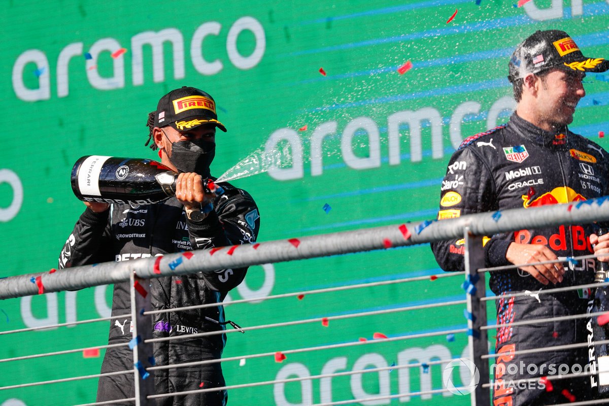 Lewis Hamilton, Mercedes, 2nd position, and Sergio Perez, Red Bull Racing, 3rd position, spray Champagne on the podium