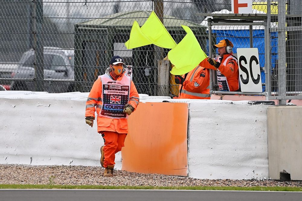 The safety car board is show as marshals wave yellow flags