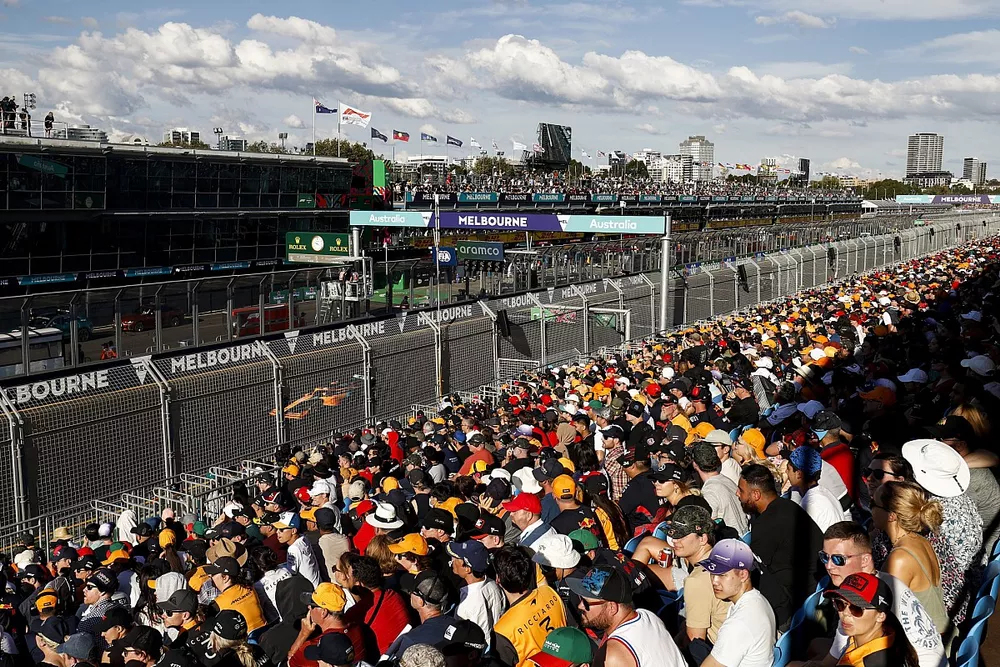 Fans watch from a grandstand as Daniel Ricciardo, McLaren MCL36, passes