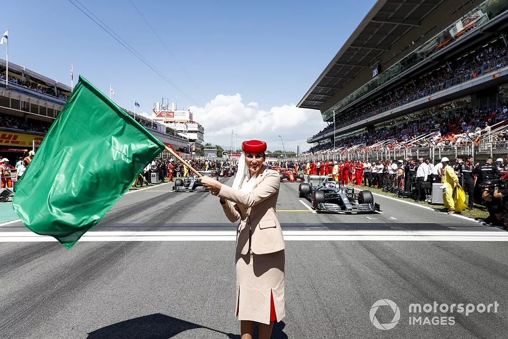 Une h&ocirc;tesse de l'air Emirates agite un drapeau vert sur la grille