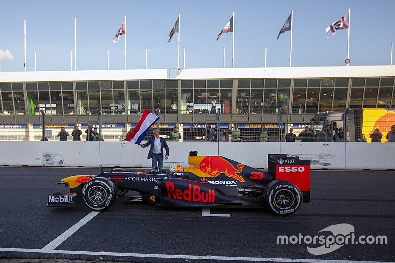 Max Verstappen, RB8, op start/finish van Circuit Zandvoort met Jan Lammers op de achtergrond die met de Nederlandse vlag zwaait