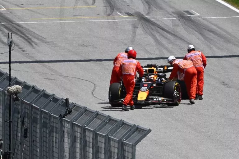 Marshals push the car of Max Verstappen, Red Bull Racing RB20, back to his garage
