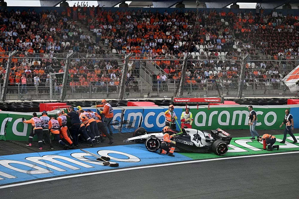 Marshals repair the barriers and deal with the damaged car of Daniel Ricciardo, AlphaTauri AT04