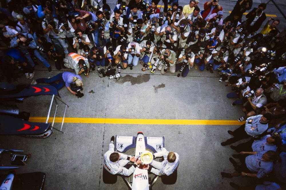 Mika Häkkinen, McLaren MP4-13 Mercedes, y David Coulthard, McLaren MP4-13 Mercedes, celebran la victoria en la carrera y el campeonato del mundo frente a un a los fotógrafos.