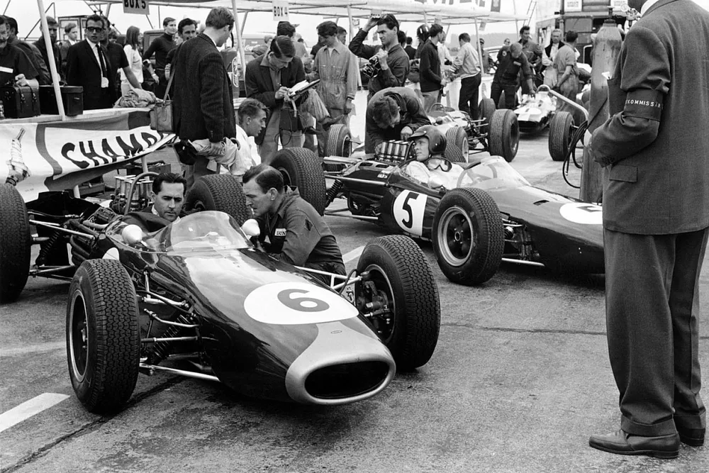 Jack Brabham, Brabham BT11 Climax and Dan Gurney, Brabham BT7 Climax wait in the pits