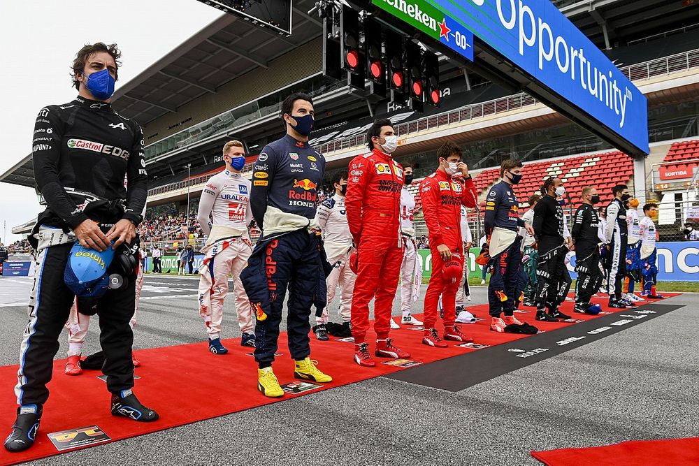 Los pilotos se ponen en pie para escuchar el himno nacional antes de la salida