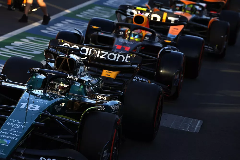 Lance Stroll, Aston Martin AMR23, Sergio P&eacute;rez, Red Bull Racing RB19, y Lando Norris, McLaren MCL60, en boxes.