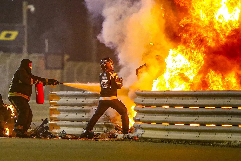 Un commissaire &eacute;teint les flammes pendant que Romain Grosjean, Haas F1, descend de sa cellule de survie
