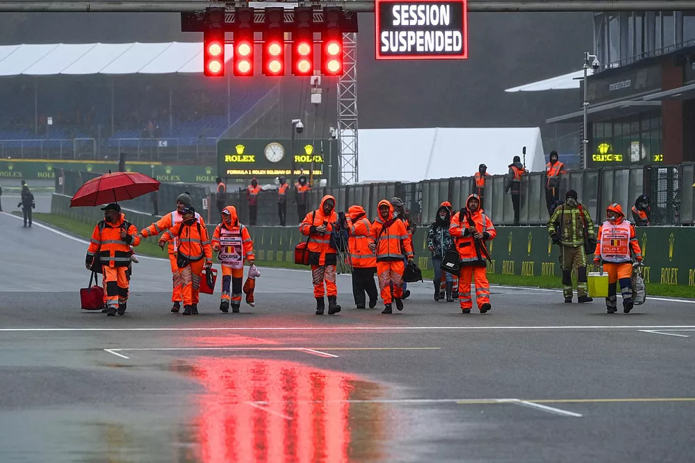 Oficiales de pista y el letrero de sesión suspendida en la parrilla