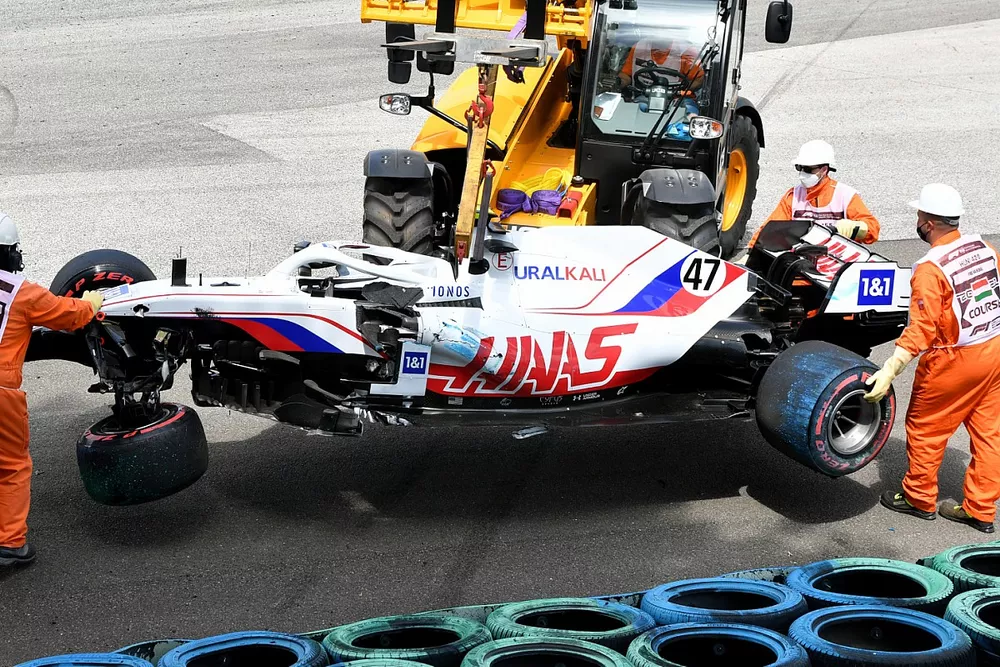 Marshals remove the damaged car of Mick Schumacher, Haas VF-21, from a tyre barrier after his crash in FP3