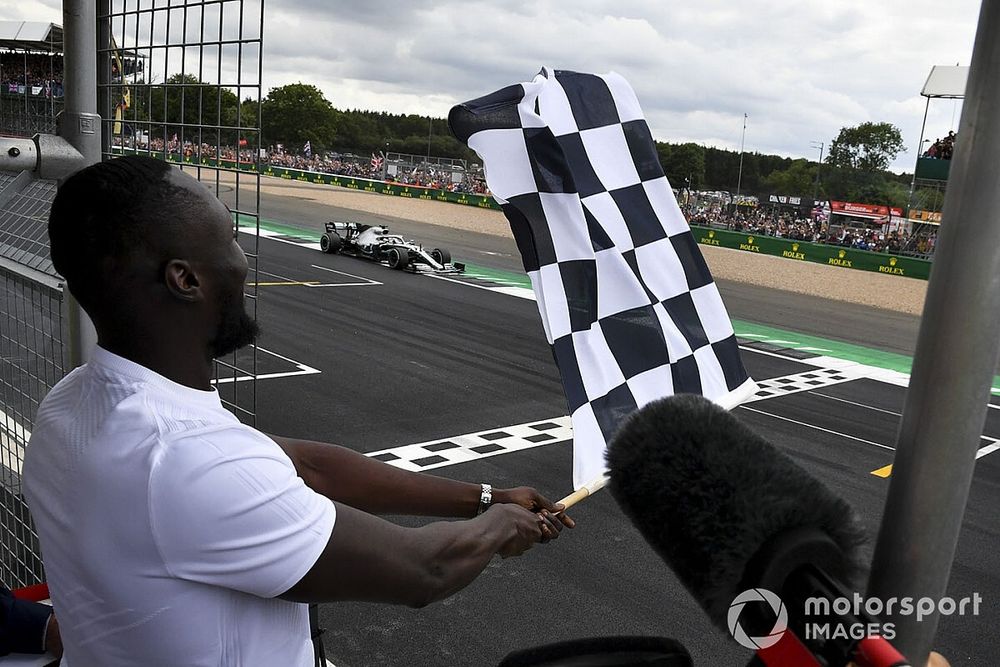 Stormzy, Rapero ondea la bandera de llegada mientras Lewis Hamilton, Mercedes AMG F1 W10 cruza la línea