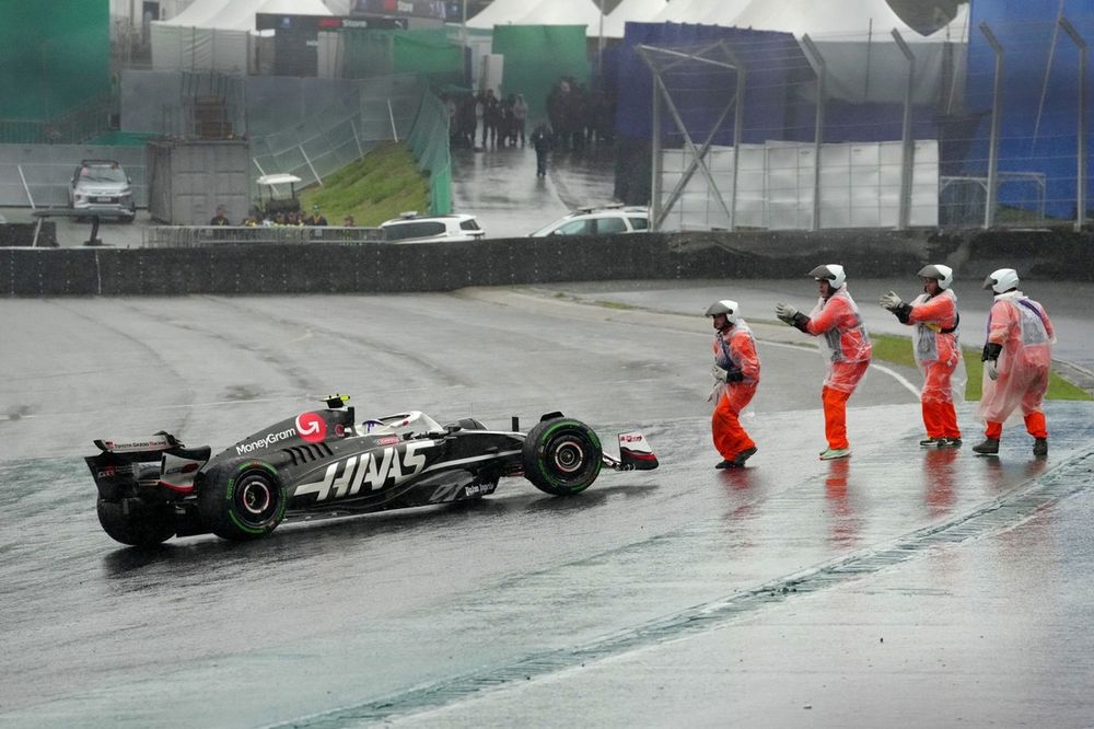 Comisarios empujan el coche de Nico Hulkenberg, Haas VF-24, de vuelta a la pista