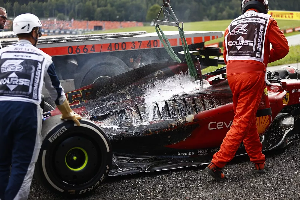 Los oficiales de pista retiran del circuito el coche incendiado de Carlos Sainz, el Ferrari F1-75