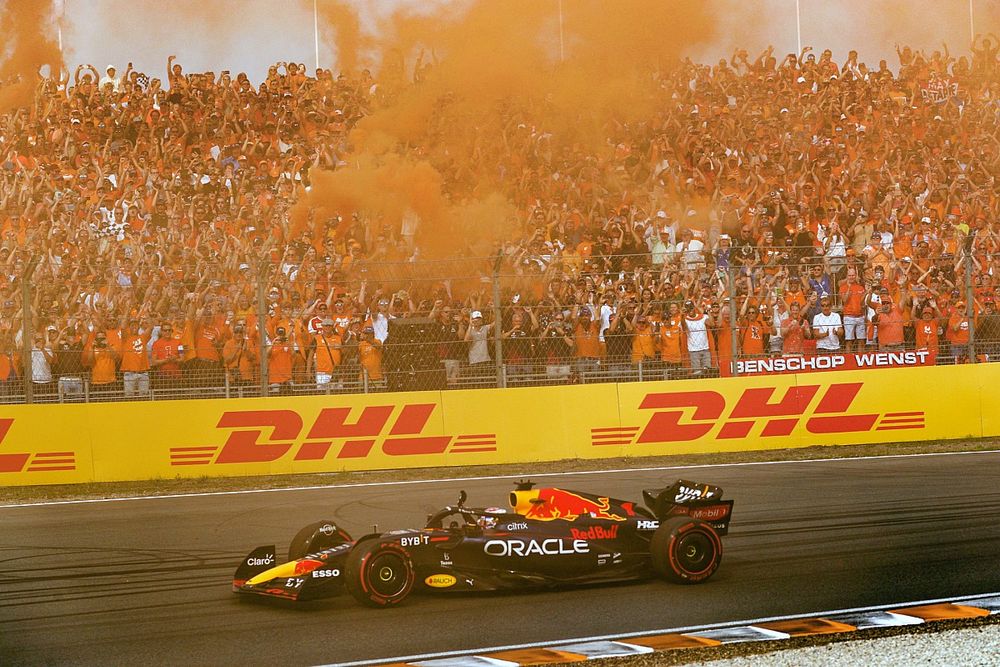 Max Verstappen, Red Bull Racing RB18, eerste plaats, zwaait vanuit zijn cockpit terwijl fans de lucht oranje kleuren om de overwinning te vieren