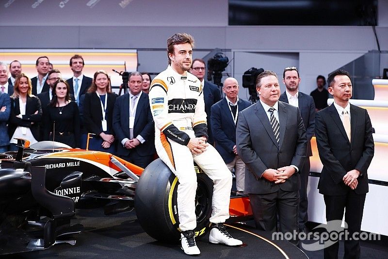 Fernando Alonso, McLaren, sits on a front wheel of the MCL32, alongside Zak Brown, Executive Director of McLaren Technology Group, and Yusuke Hasegawa, Senior Managing Officer, Honda