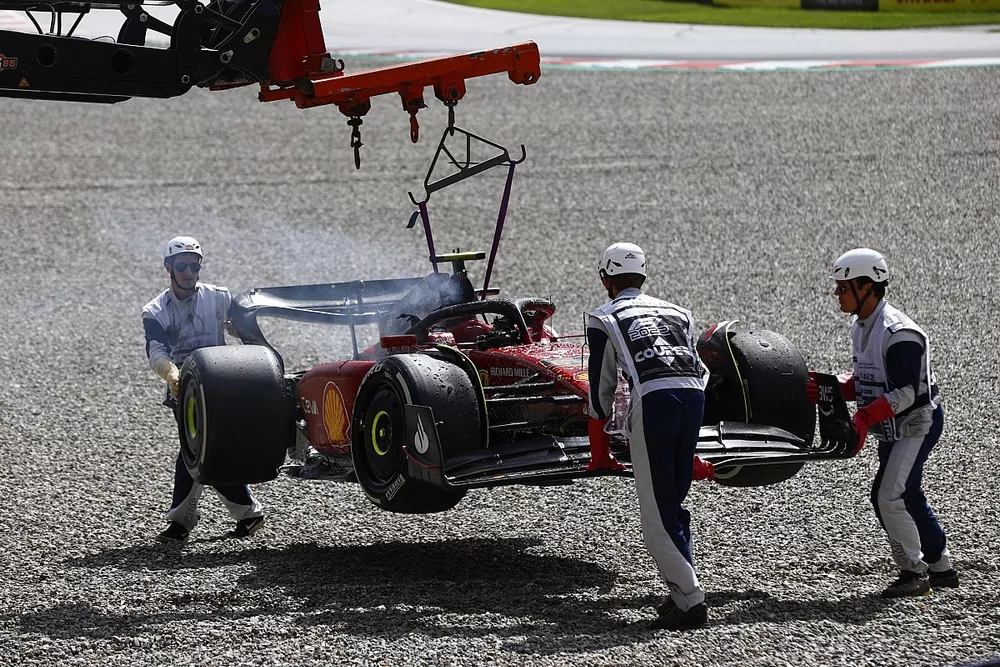 Los oficiales de pista retiran del circuito el coche incendiado de Carlos Sainz, el Ferrari F1-75