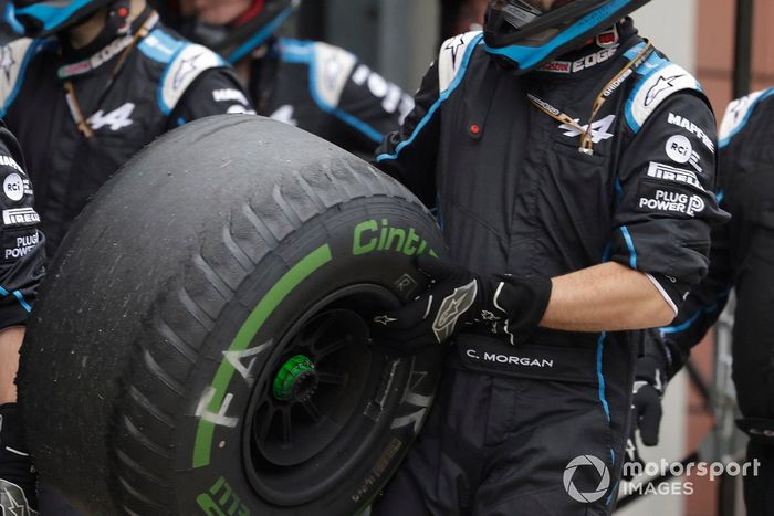 Un miembro del equipo de boxes de Alpine F1 con un neumático intermedio desgastado

