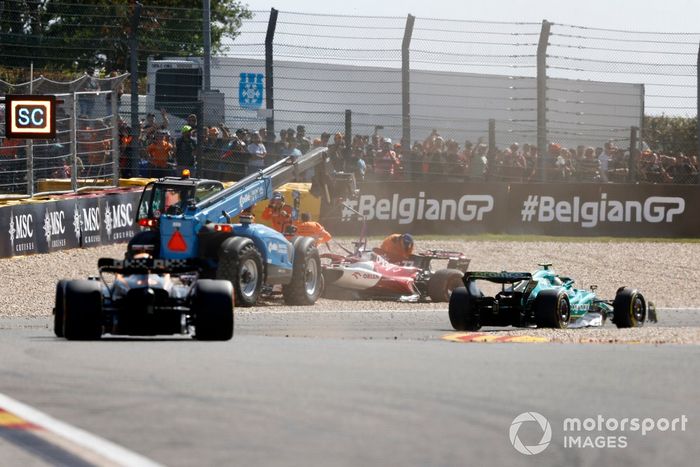 Sebastian Vettel, Aston Martin AMR22, Daniel Ricciardo, McLaren MCL36, pasa junto al coche varado de Valtteri Bottas, Alfa Romeo C42, mientras es asistido por los oficiales de pista