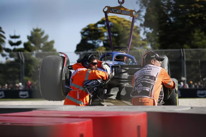 Oficiales de pista retiran del circuito el coche dañado de Alex Albon, Williams FW45
