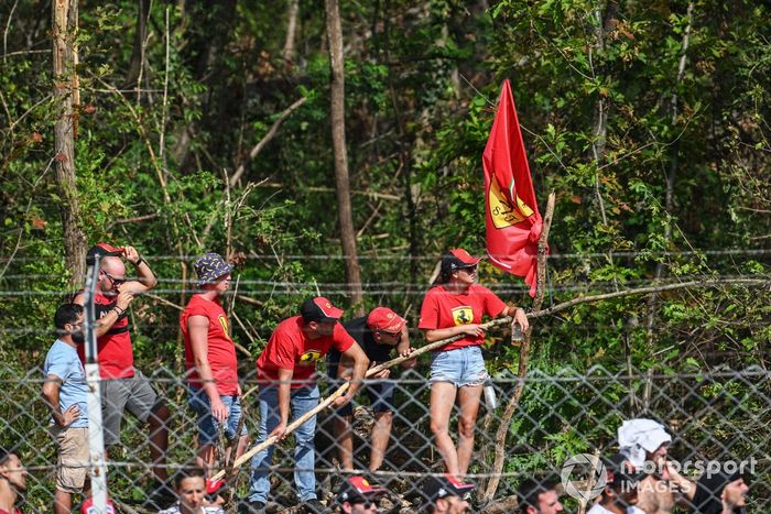 Los aficionados de Ferrari se suben a una valla para ver mejor