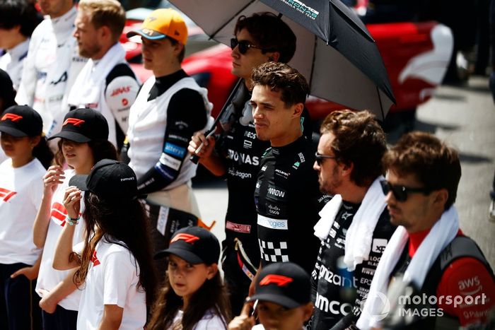 George Russell, Mercedes-AMG, Lando Norris, McLaren, Fernando Alonso, Aston Martin F1 Team, en la parrilla con los niños de la parrilla para el himno nacional.