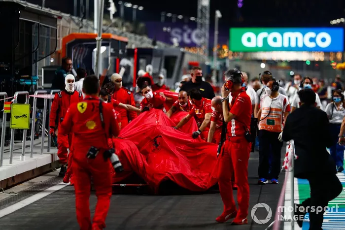 Los mecánicos de Ferrari con el coche dañado de Charles Leclerc, Ferrari SF21, en el pit lane