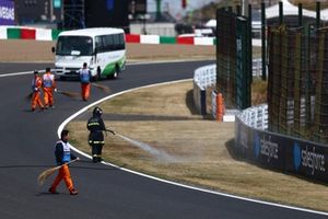 Un bombero rocía la hierba del lateral de la pista para humedecerla tras los incendios ocurridos durante los entrenamientos finales.