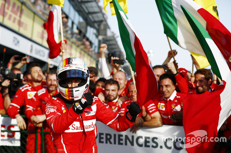 Гонщик Ferrari Себастьян Феттель празднует победу вместе с командой