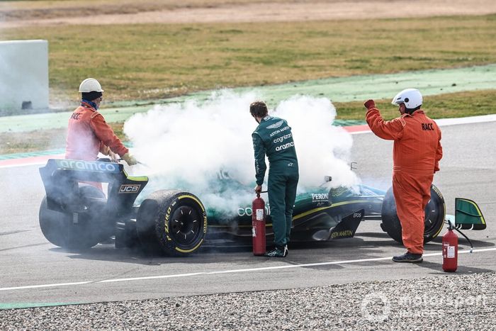 Oficiales de pista asisten a Sebastian Vettel, Aston Martin AMR22, después de que un fallo técnico produzca humo