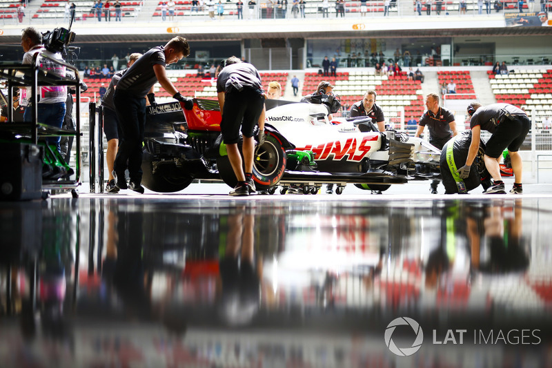 Mekanik memasukkan mobil Romain Grosjean, Haas F1 Team VF-18, ke garasi