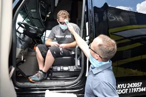 A driver for a team hauler has their temperature checked