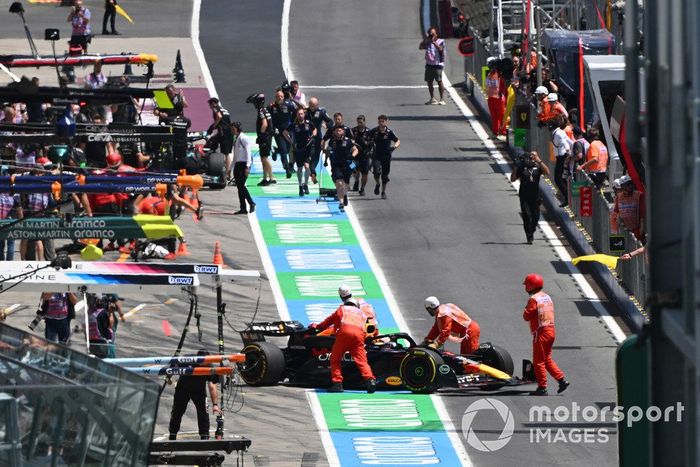 Los comisarios empujan el coche parado de Max Verstappen, Red Bull Racing RB20, en el pit lane