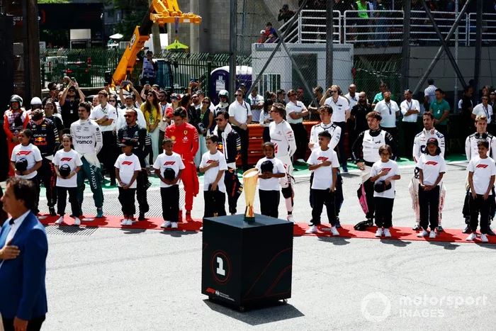 Los pilotos en la parrilla con los niños de la parrilla para el himno nacional