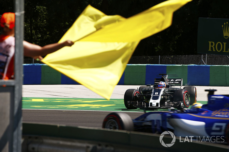 Oficiales ondean bandera amarilla con Romain Grosjean, Haas F1 Team VF-17. Marcus Ericsson, Sauber C36 pasa por la zona del incidente