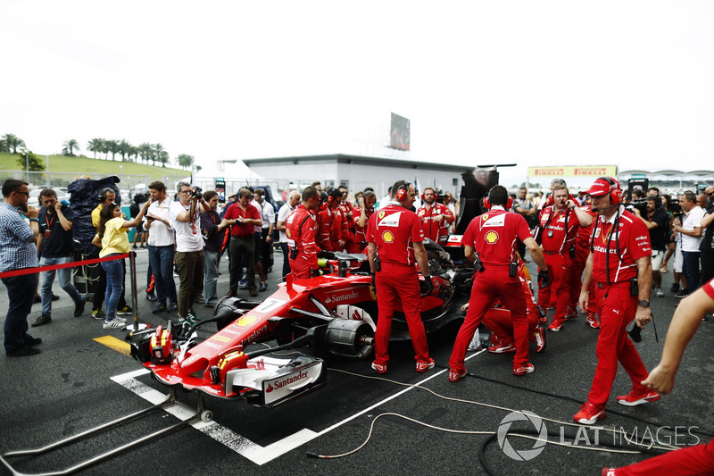 The Ferrari team frantically try to fix the Kimi Raikkonen Ferrari SF70H on the grid, Journalist Jonathan Noble looks on it