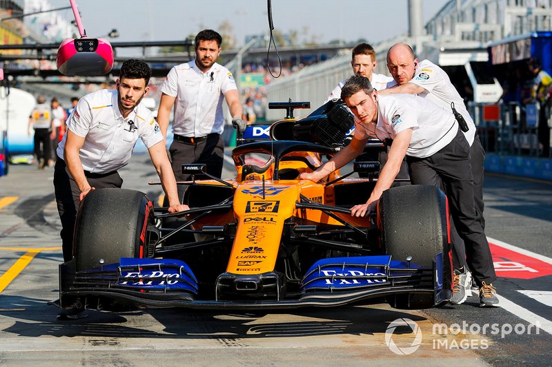 McLaren mechanics move the car of Carlos Sainz Jr., McLaren MCL34