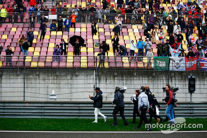 Lewis Hamilton, Mercedes AMG, gives caps to fans during a weather delay in FP2