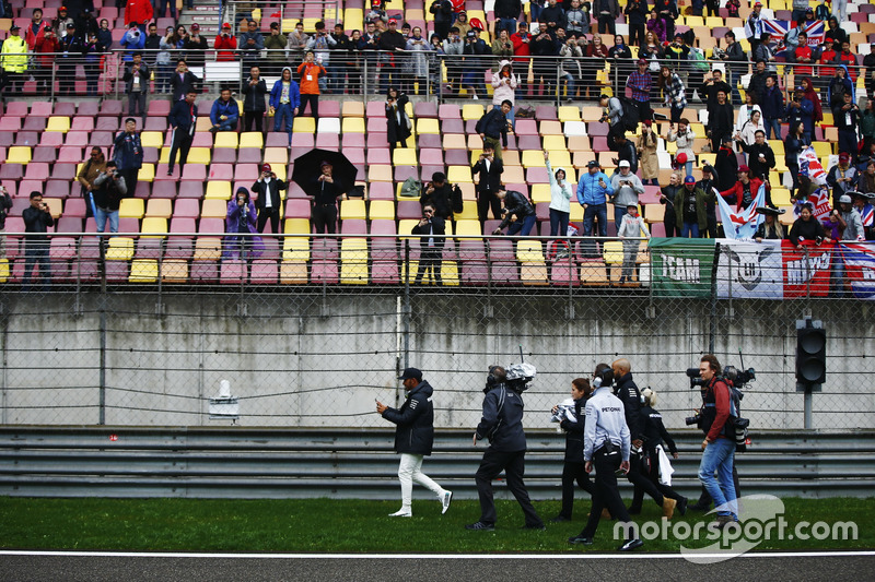 Lewis Hamilton, Mercedes AMG, gives caps to fans during a weather delay in FP2.  World