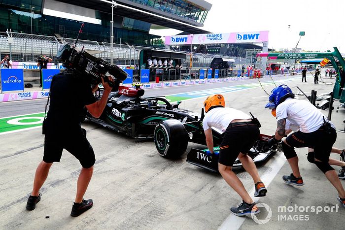 Miembros del equipo de pits de McLaren intentan asistir a Valtteri Bottas, Mercedes W12, después de que hizo un trompo en el pit lane