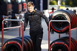 A McLaren mechanic wheels a trolley of Pirelli tyres