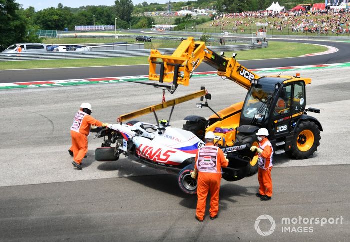 Los oficiales retiran el coche dañado de Mick Schumacher, Haas VF-21, de una barrera de neumáticos tras su accidente en la FP3