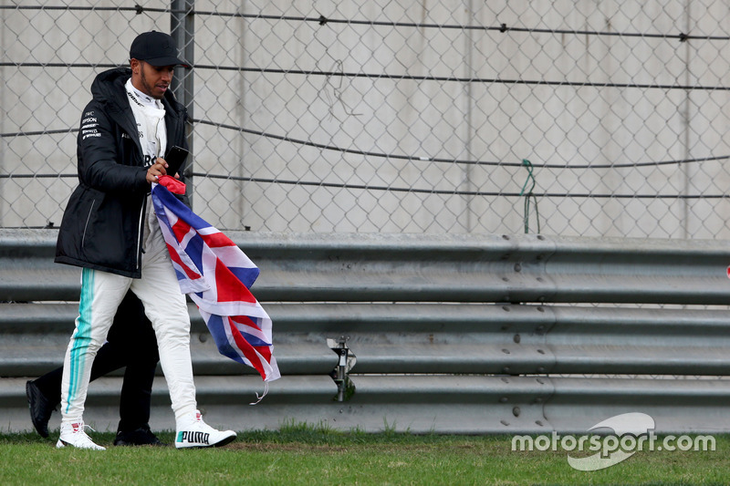 Lewis Hamilton, Mercedes AMG, attraversa la pista per intrattenere i tifosi e raccoglie una bandiera