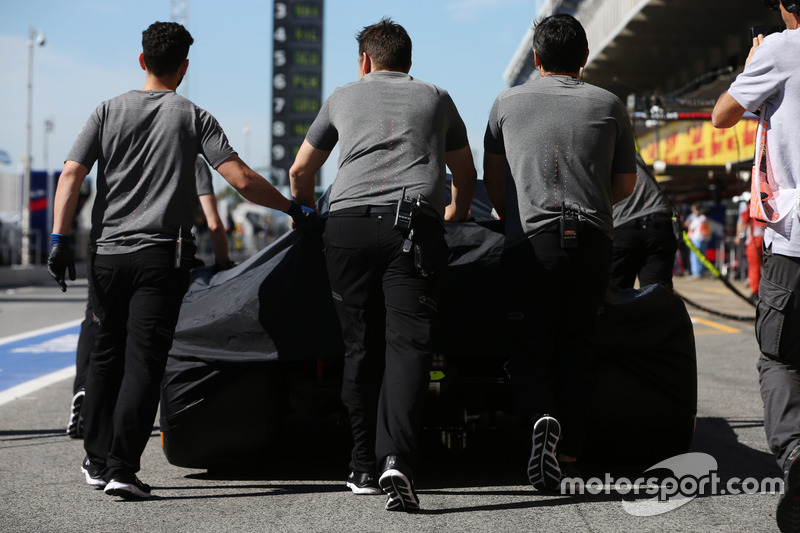 McLaren engineers move the car of Fernando Alonso, McLaren MCL32, in the pit lane, under covers