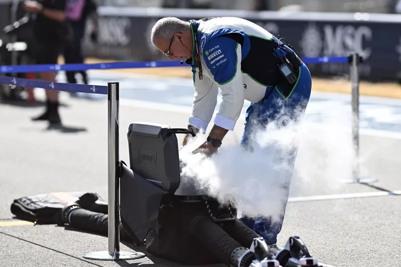Racing Bulls team member on the grid with cooling equipment