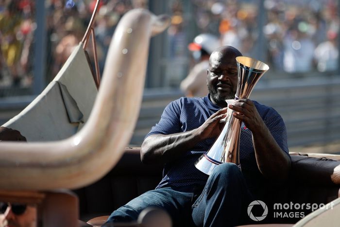 La ex estrella del baloncesto Shaquille O'Neal llega a la ceremonia del podio con el trofeo