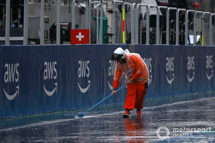 Un comisario barre el agua en el pit lane