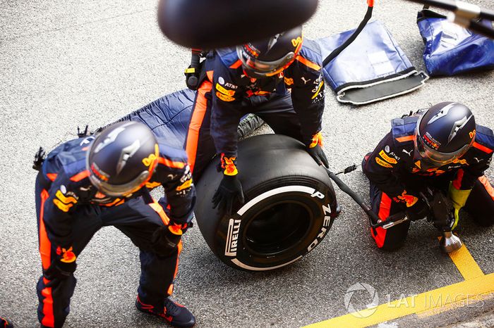 Los mecánicos de Red Bull esperan fuera de su garaje con un neumático Pirelli